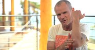 Flea, baixista do Red Hot Chili Peppers, mostrando a lesão no braso causada por um acidente enquanto ele praticava snowboarding - Reprodução/Vídeo
