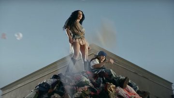 Charli XCX e Billie Eilish sobre pilha de roupas em videoclipe do remix de 'Guess' (Foto: Reprodução)