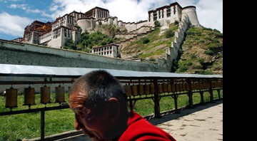 Monge caminha em Lhasa, em frente ao Palácio Potala - que já foi sede do governo tibetano - Eugene Hoshiko/AP