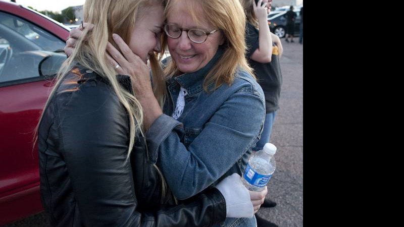 Emma Goos, 19, abraça a mãe, Judy Goos, do lado de fora da Gateway High School, onde testemunhas dão depoimentos sobre o crime. Emma estava na terceira fileira do cinema no qual o atirador matou 12 pessoas. Ela ajudou um homem que foi ferido 

 - AP