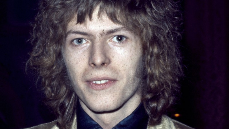 Bowie surge com os cabelos loiros e cacheados sobrando na cabeça, em fotografia feita no dia 1º de janeiro de 1969, ano em que o artista lançaria seu primeiro disco a ter relativo sucesso: <i>Space Oddity</i>. - Rex Features/AP