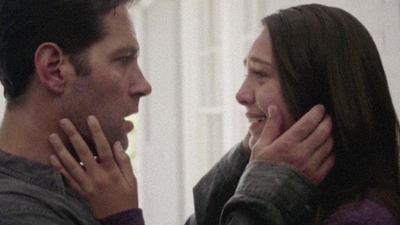 Paul Rudd e Emma Fuhrmann frente a frente, com as mãos nos rostos um do outro.