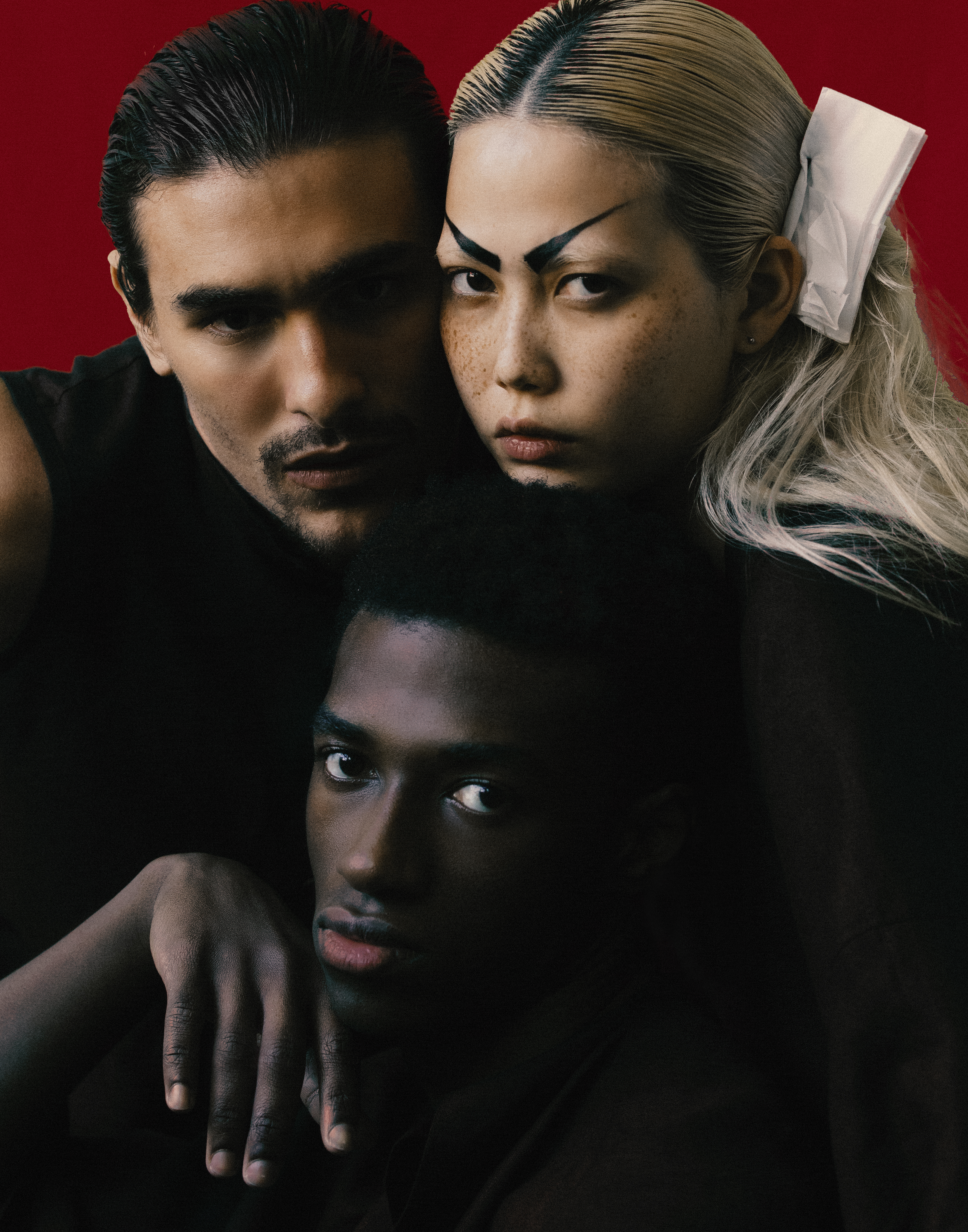 três modelos vestindo roupas pretas da j boggo e posando num fundo vermelho