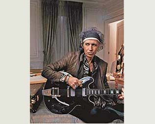 Keith posa ao lado de um case de guitarra com a estampa característica da Louis Vuitton