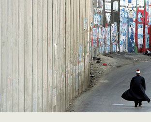 Em 2006, um cidadão palestino caminha ao lado do que Israel chama de "Cerca de Segurança", na cidade de Abu Dis