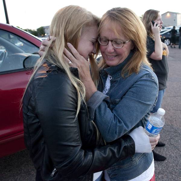 Emma Goos, 19, abraça a mãe, Judy Goos, do lado de fora da Gateway High School, onde testemunhas dão depoimentos sobre o crime. Emma estava na terceira fileira do cinema no qual o atirador matou 12 pessoas. Ela ajudou um homem que foi ferido
