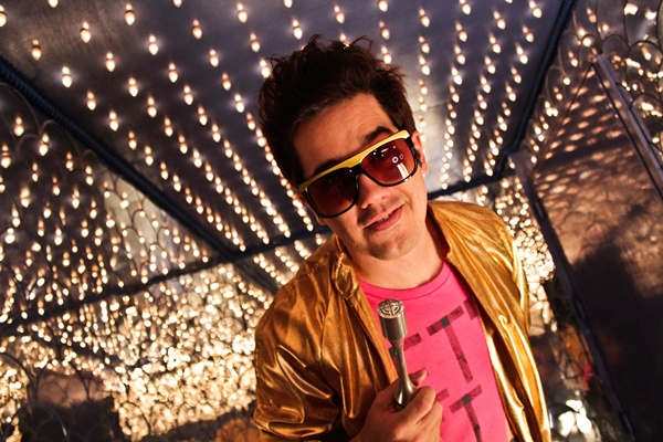 Rogério Flausino de figurino colorido fazendo pose nos bastidores da gravação