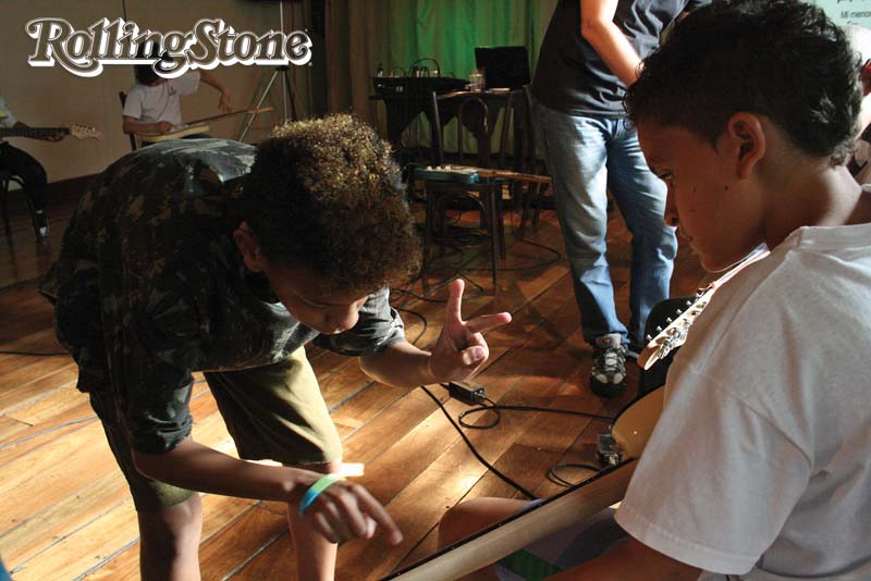 LIÇÕES DE VIDA  Vinicius ensina seu colega a fazer seus primeiros acordes;