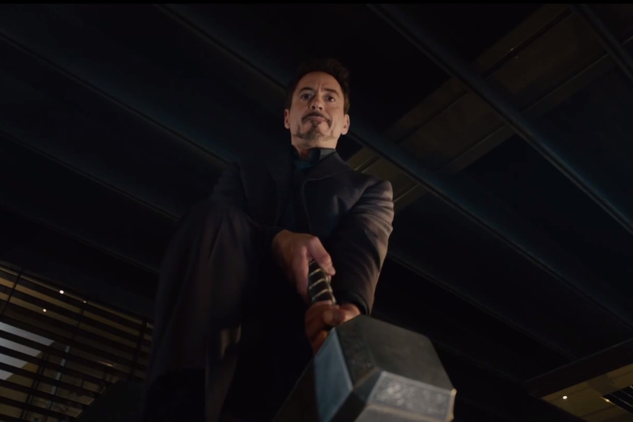 Tony Stark (Robert Downey Jr.) tenta levantar o martelo de Thor, sem sucesso, em cena do trailer estendido de Vingadores: Era de Ultron