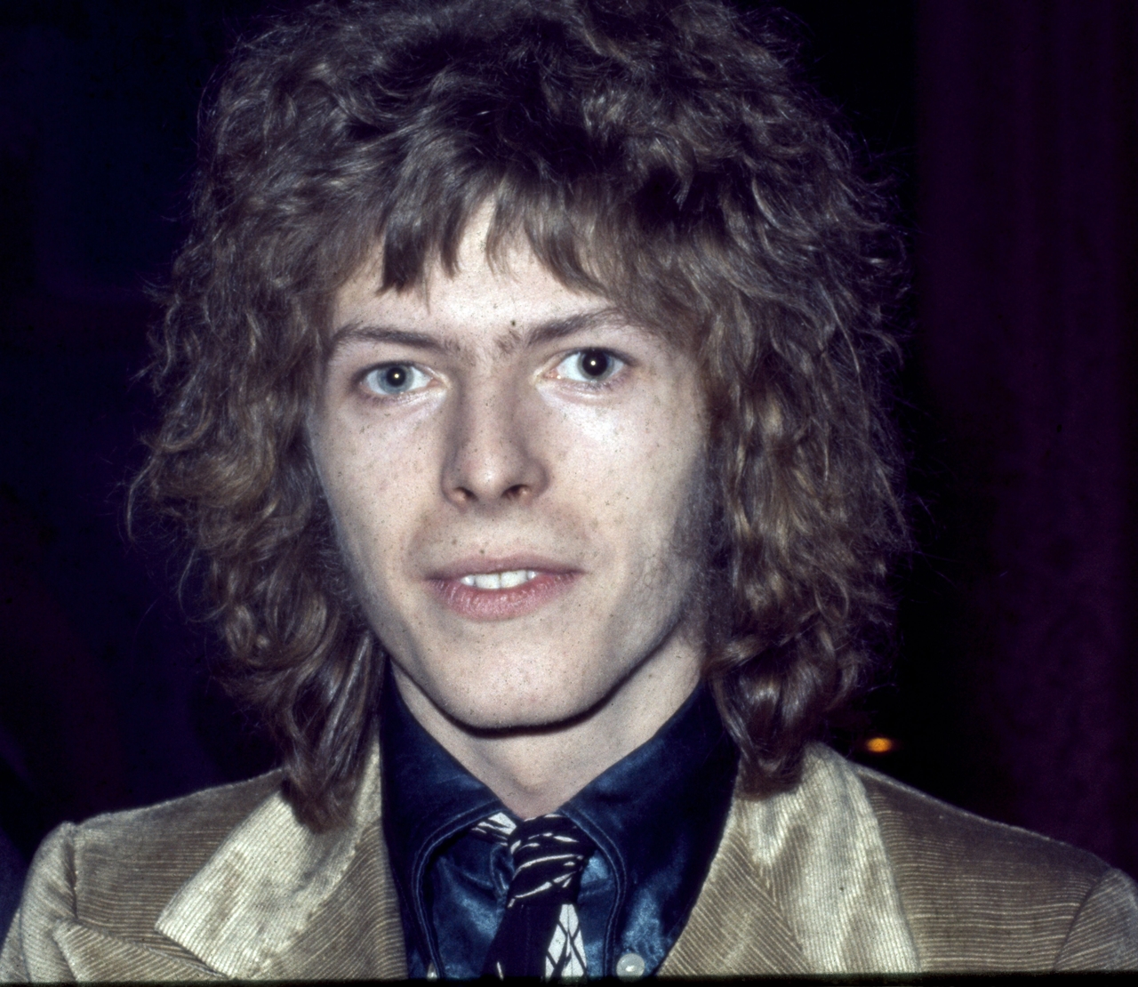 Bowie surge com os cabelos loiros e cacheados sobrando na cabeça, em fotografia feita no dia 1º de janeiro de 1969, ano em que o artista lançaria seu primeiro disco a ter relativo sucesso: Space Oddity.