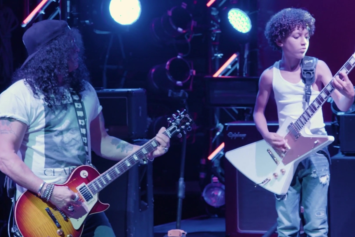 Cena de vídeo do guitarrista do Guns N' Roses, Slash, tocando com os jovens do musical da Broadway de Escola de Rock, durante um ensaio
