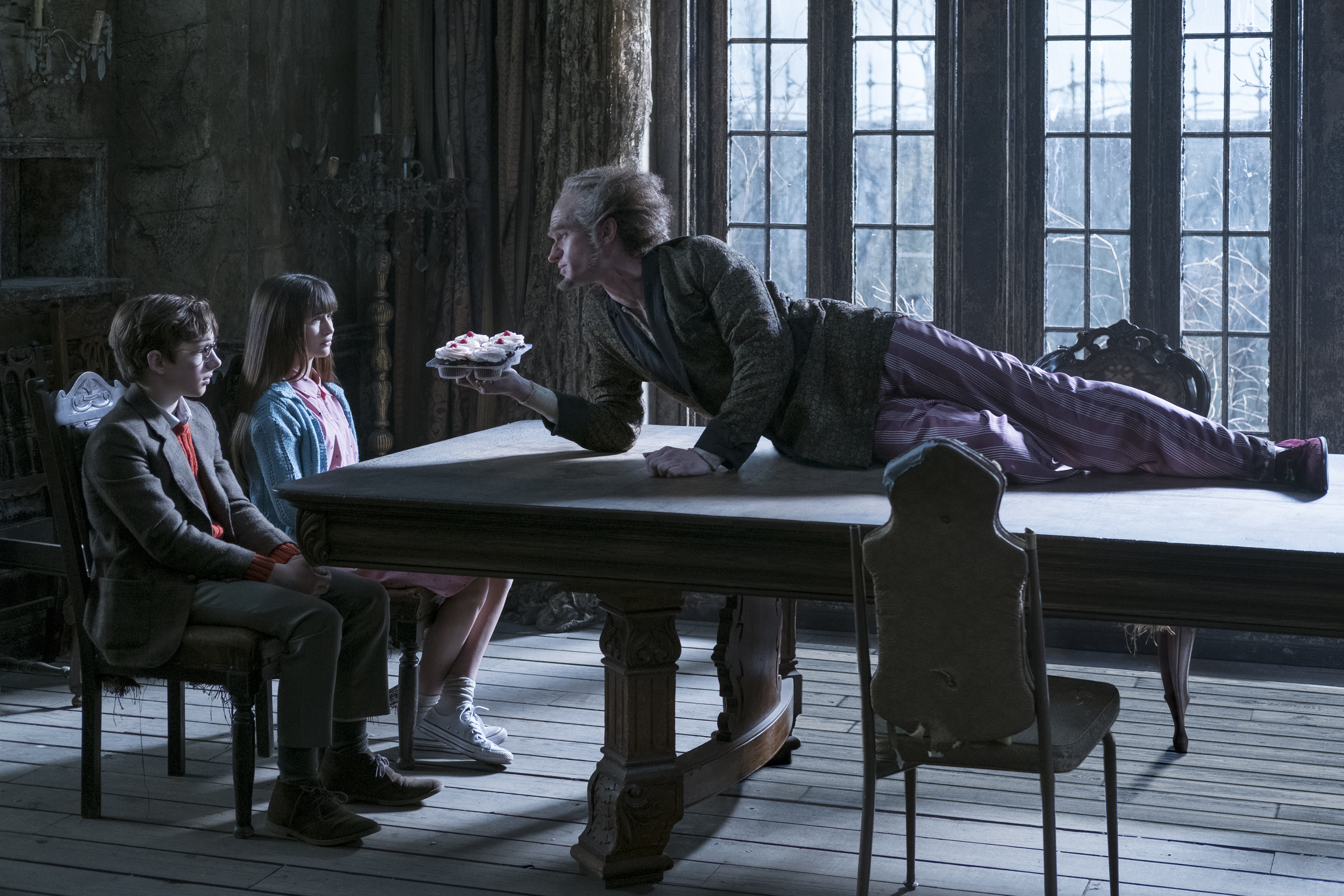 Conde Olaf (Neil Patrick Harris) e os três irmãos órfãos: Violet (Malina Weissman), Klaus (Louis Hynes) e Sunny Baudelaire
