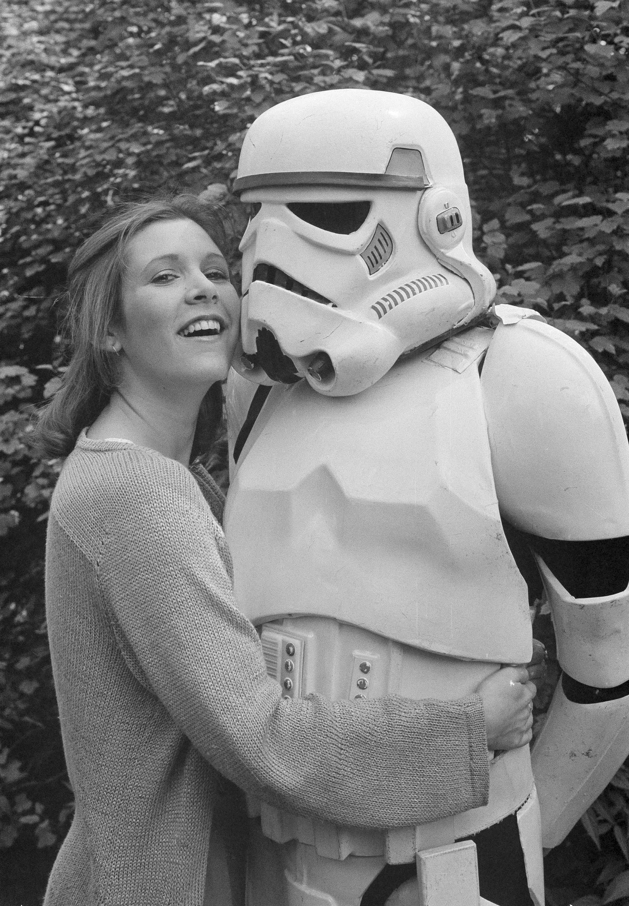 Carrie Fisher posando ao lado de um Stormtrooper em Londres, Inglaterra, no dia 23 de maio de 1980. A atriz estava na cidade divulgando o filme Star Wars: Episódio V - O Império Contra-Ataca.