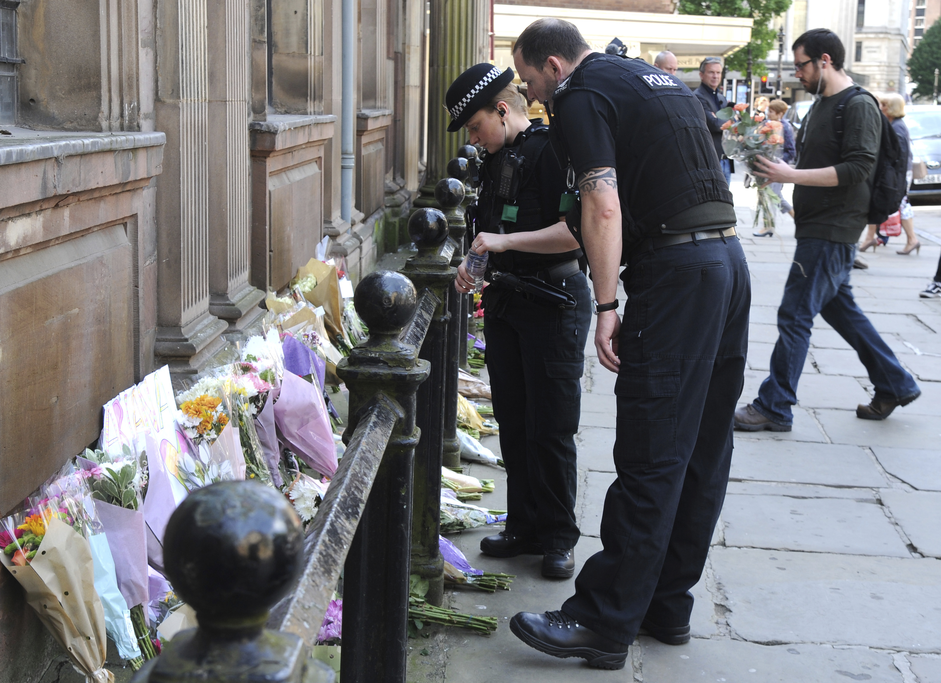 Policiais observam os tributos às vítimas do show do ataque terrorista ocorrido no show da cantora Ariana Grande em Manchester, na Inglaterra, em 23 de maio de 2017. As homenagens foram colocadas na praça St. Ann.
